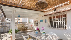 A patio with a table and chairs, potted plants, and a pergola with a woven ceiling. - 2299 Villetta Noemi (Porto Cesareo)
