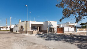 Een woonstraat met moderne huizen, een heldere lucht en een boom die schaduwen werpt.