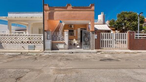 Un immeuble résidentiel doté d’une entrée sécurisée par un portail, d’un escalier menant au deuxième étage et d’un petit patio avec une table et des chaises.