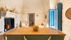 Una cocina rústica con una mesa de madera, un cuenco de fruta y una puerta azul.
