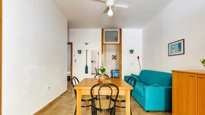 A dining area with a wooden table and chairs, a teal sofa, and a wooden cabinet. - 2019 Villetta del Colle (Porto Cesareo)