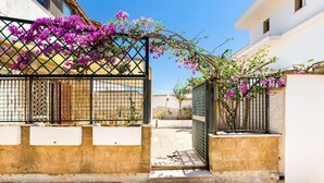 A gated entrance with a metal gate and a concrete pathway leading to a building. - 2019 Villetta del Colle (Porto Cesareo)