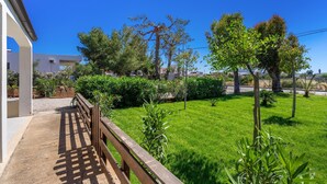 Un jardin bien entretenu, avec une clôture en bois, un ciel bleu dégagé et un bâtiment en arrière-plan.