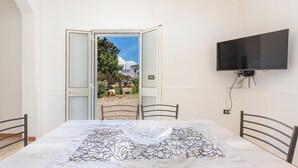 Une chambre avec un lit, un téléviseur fixé au mur et une porte donnant sur un espace extérieur.