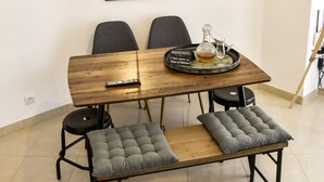 A dining area with a wooden table, two grey cushioned benches, a black tray with a bottle, and a mirror above the table. - Alohamundi San Leandro (Sevilla)