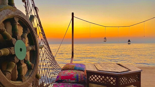 A hammock with colorful cushions on a wooden deck overlooking the sea at sunset. - Happy Land Hotel (Dahab)