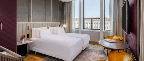 A modern hotel room with a large bed, two bedside tables, a small round table, and a TV.