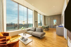 Una sala de estar moderna con un ventanal grande, un sofá gris, una mesa de centro blanca y piso de madera.
