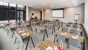 A conference room with multiple tables and chairs, a projector screen, and a whiteboard. - NH Collection Copenhagen (Copenhagen)