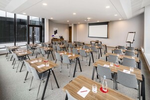A conference room with multiple tables and chairs, a projector screen, and a whiteboard.