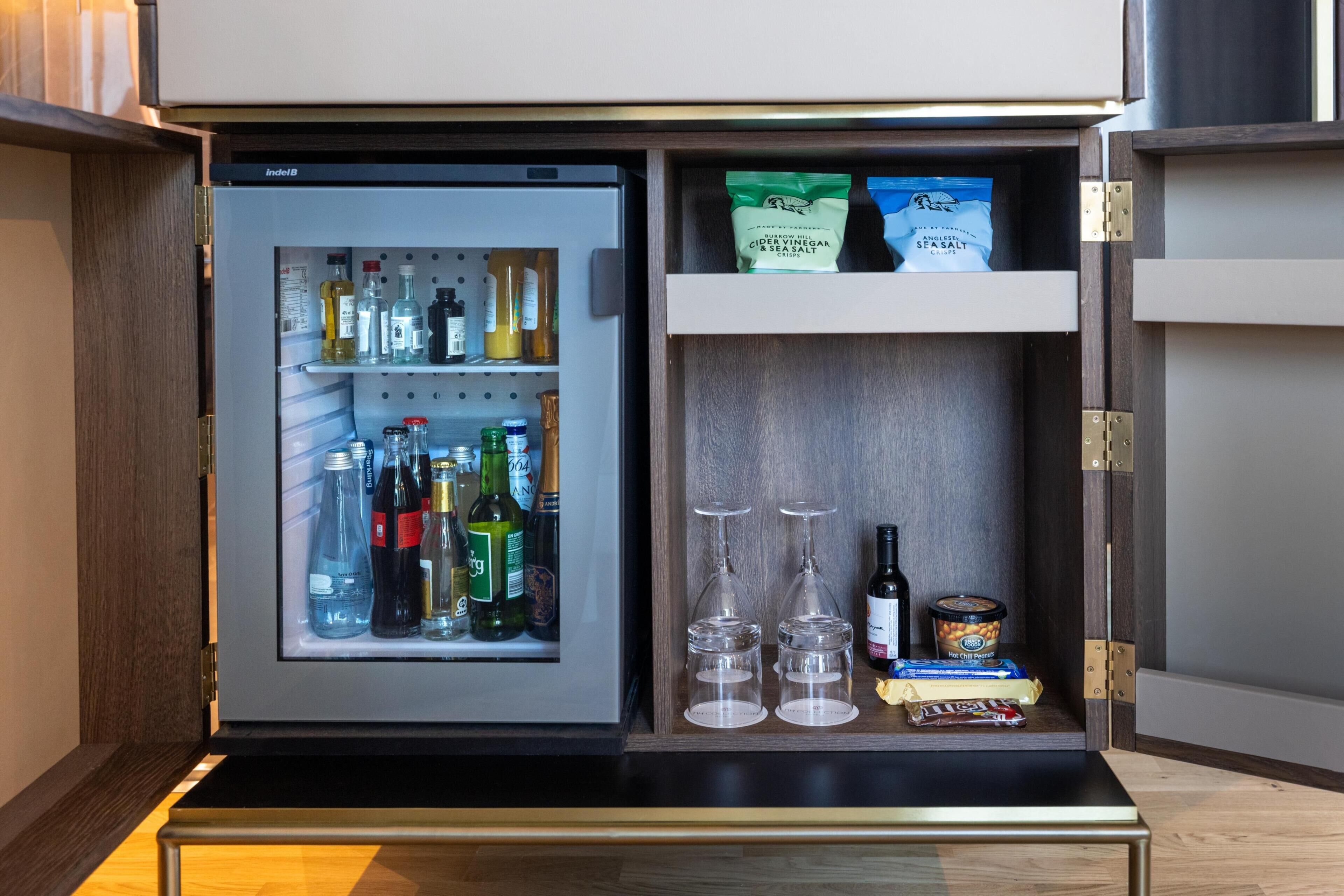A mini-fridge with various beverages and snacks.