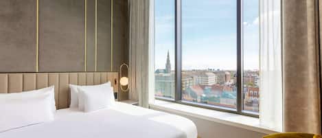 Une chambre d’hôtel avec un grand lit, une vue sur la ville et un design moderne.