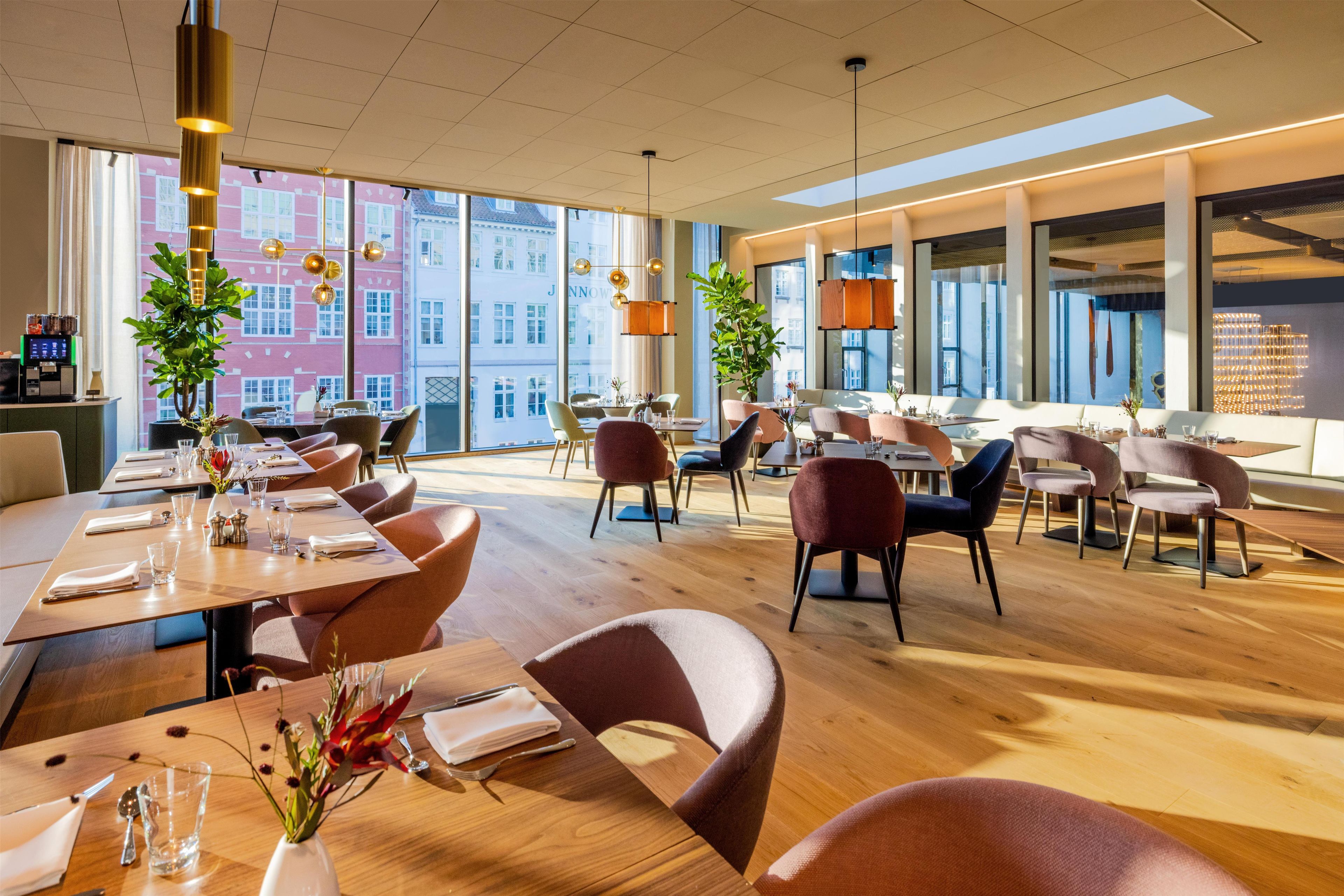 En rymlig restaurang med högt i tak, stora fönster och modern inredning.