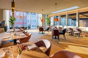 Un restaurante espacioso con techos altos, ventanas amplias y mobiliario moderno.