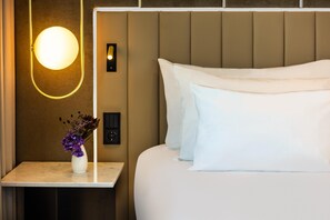 A hotel room with a bed, a nightstand, a vase with flowers, a wall-mounted light, and a control panel. - NH Collection Copenhagen (Copenhagen)