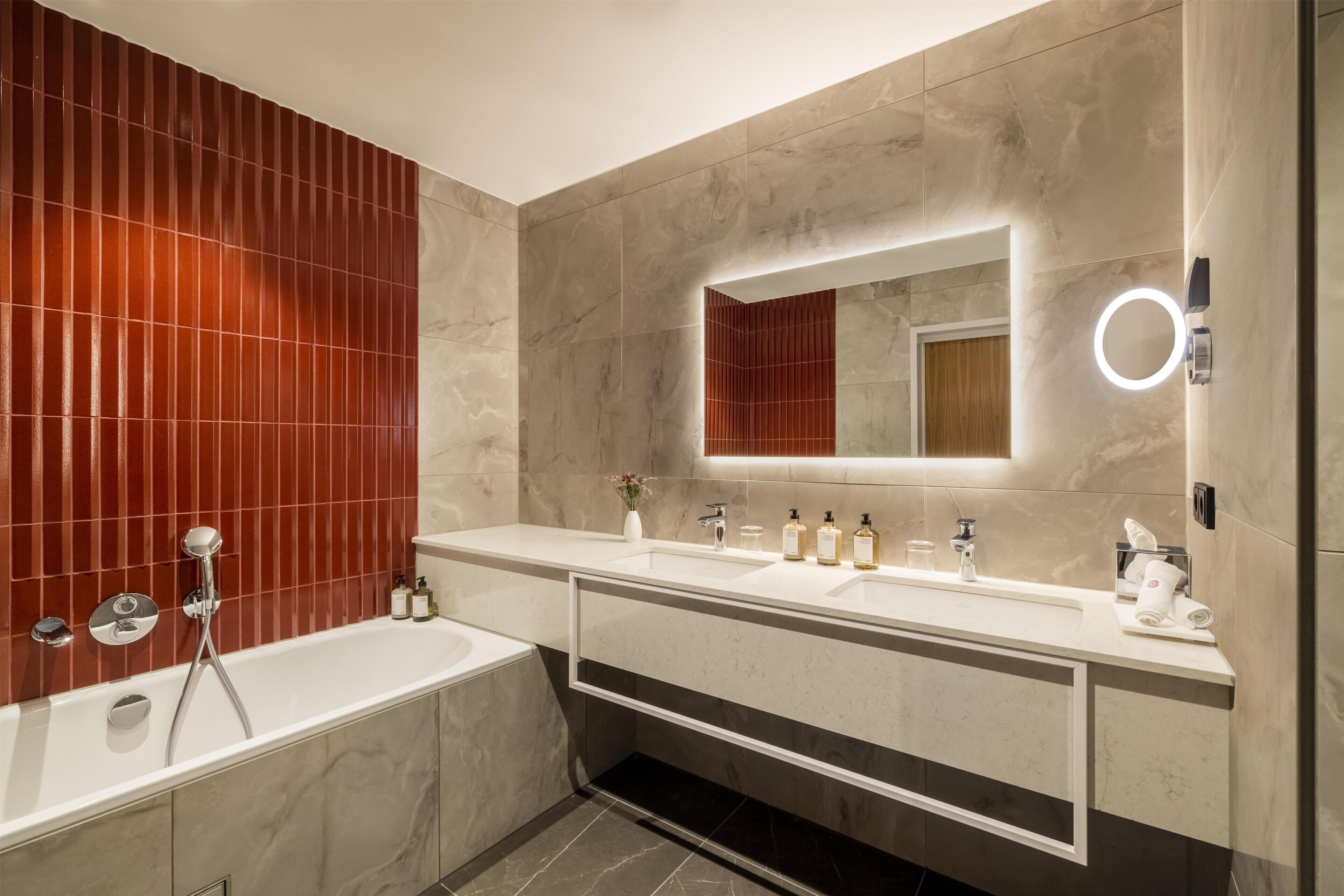 A modern bathroom with a bathtub, two sinks, and a vanity with a mirror.