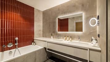 A modern bathroom with a bathtub, two sinks, and a vanity with a mirror.