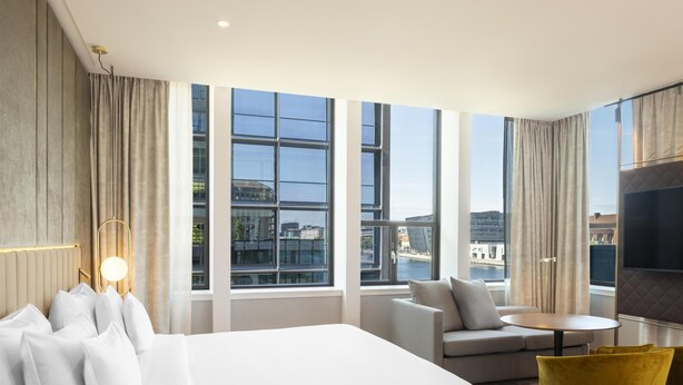 A modern hotel room with a large bed, a sofa, a small table, and a TV. - NH Collection Copenhagen (Copenhagen)