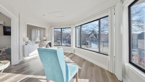 Une pièce spacieuse avec de grandes fenêtres, une cuisine moderne et une chaise bleue.