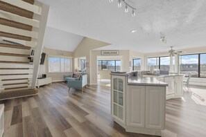 Amplia sala de estar con escalera, cocina con isla grande y vistas al exterior.