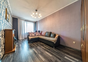 Relax in this stylish living room with a sectional sofa, wooden floor, and a unique chandelier.