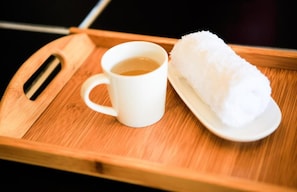 Un plateau sur lequel se trouvent une tasse blanche et une boule de riz blanche, le tout posé sur une surface en bois.