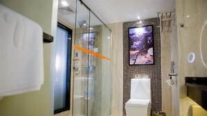 A modern bathroom with a glass shower enclosure, a toilet, and a large TV mounted on the wall. - Lavande Hotel Shenzhen Shiyan Bus Station (Shenzhen)