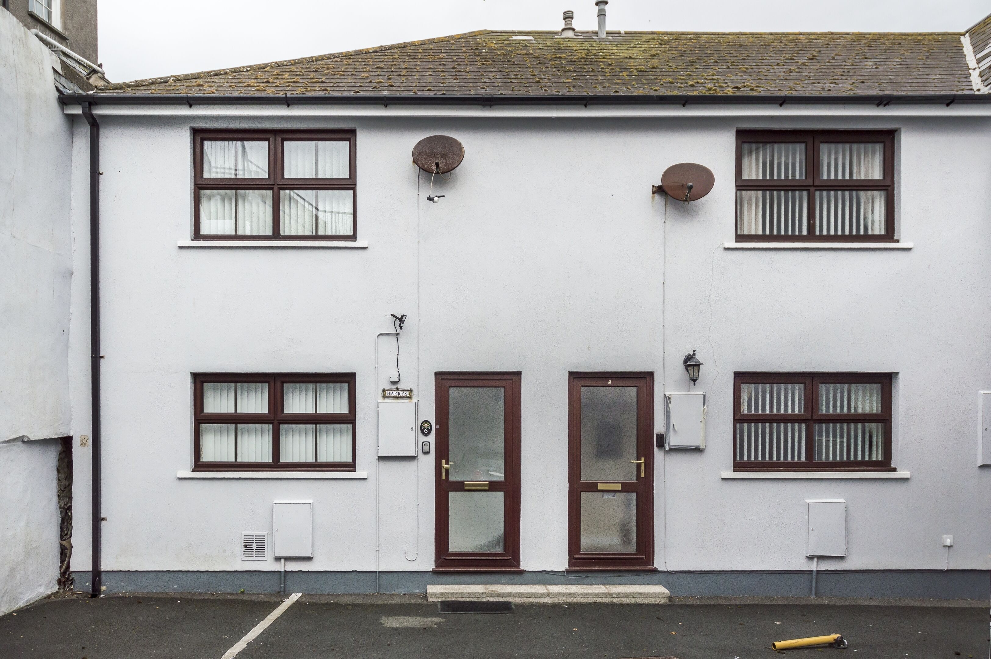 A white building with two doors, multiple windows, and satellite dishes.