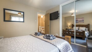 A bedroom with a bed, a mirror, a television, and a sliding door leading to another room.