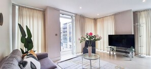 Relax in this cozy space with a comfortable sofa set, flat-screen TV, and a potted plant.