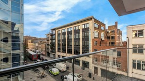 A modern building with large windows and a glass facade, located in an urban setting with visible streets and parked vehicles. - Two Bed Serviced Apt in Old Street (London)