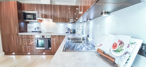 Enjoy cooking in this well-equipped kitchen with a microwave, oven, and coffee maker, along with a sink and ample cabinetry.