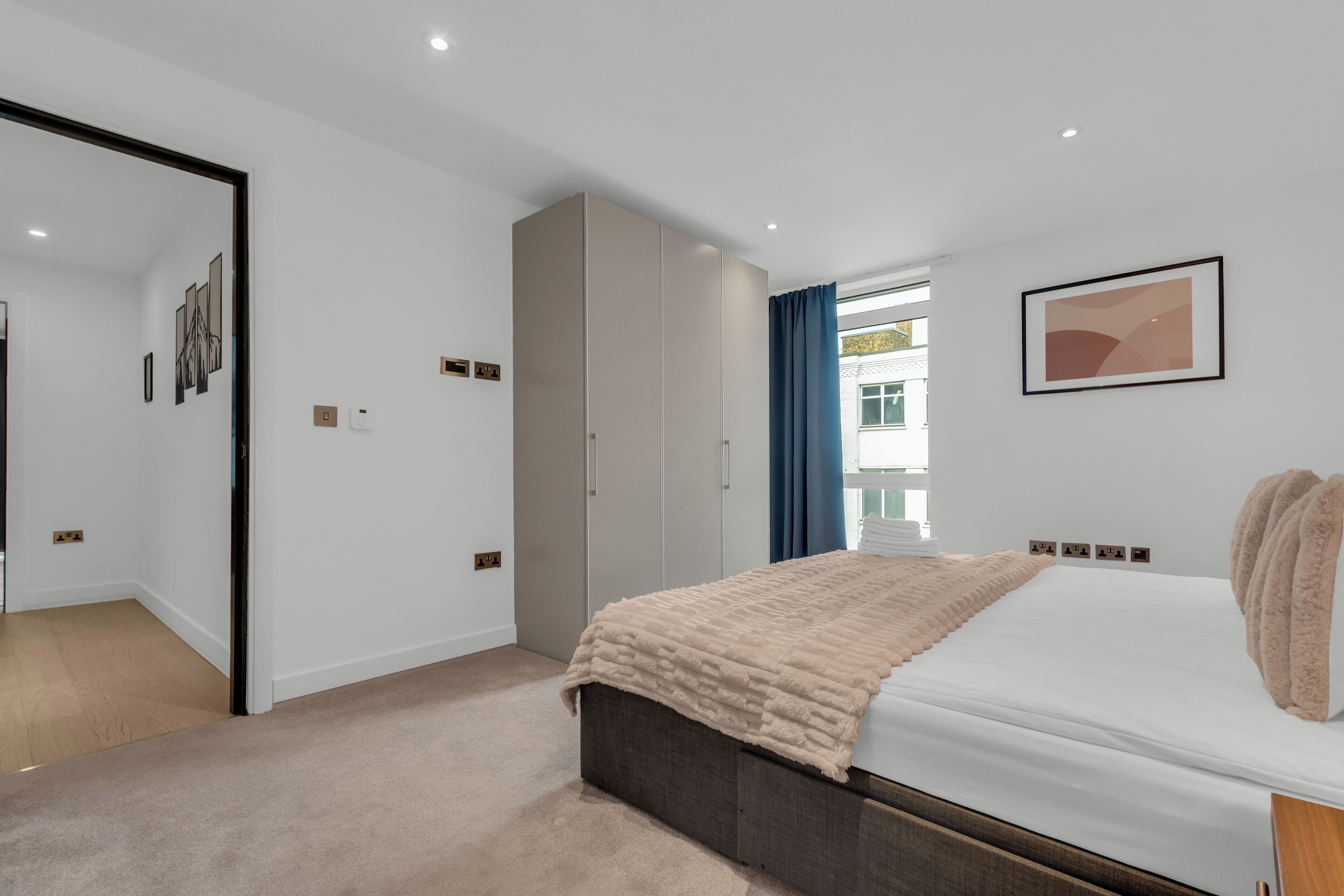 A modern bedroom with a large bed, a wardrobe, and a mirror.