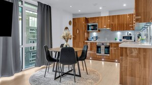 A modern kitchen with wooden cabinets, a microwave, and a built-in oven. - Two Bed Serviced Apt in Old Street (London)