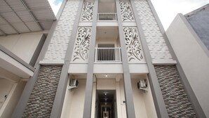 Een gebouw met een centrale ingang, decoratieve verticale versieringen en een gebeeldhouwd gevelontwerp.