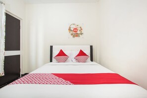 A bed with a white and red bedspread, two red pillows, and a wall decoration above the bed. - OYO 3350 Cozy Residence Syariah (Malang)