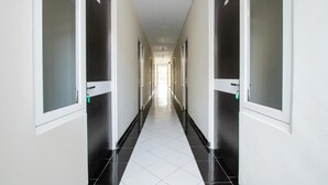 Een lange, smalle gang met deuren aan beide kanten, die naar afzonderlijke kamers leidt.