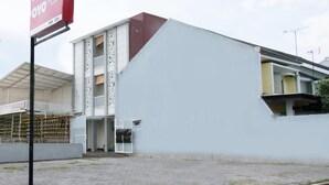 Een modern gebouw met een witte gevel en een rood naambord.