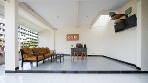 Een receptiegebied met een bank, stoelen, een bijzettafeltje en een bordje met de tekst 'OYO'.