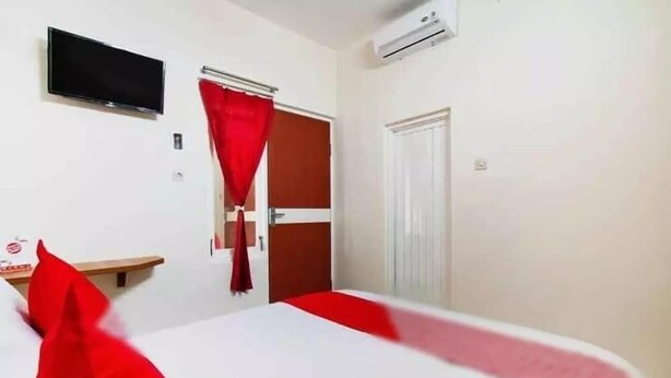 Een hotelkamer met een bed, een aan de muur bevestigde televisie en een airconditioning.