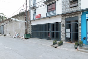 Un bâtiment portant l’enseigne RedDoorz, doté d’une entrée sécurisée par un portail et d’une porte bleue.