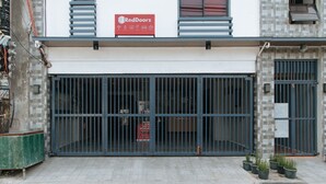 Een gesloten winkel met een RedDoorz bord, metalen hekken en plantenbakken op het trottoir.