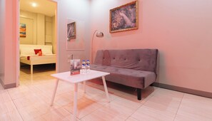 Een moderne woonkamer met een grijze bank, een witte salontafel en een schilderij aan de muur.