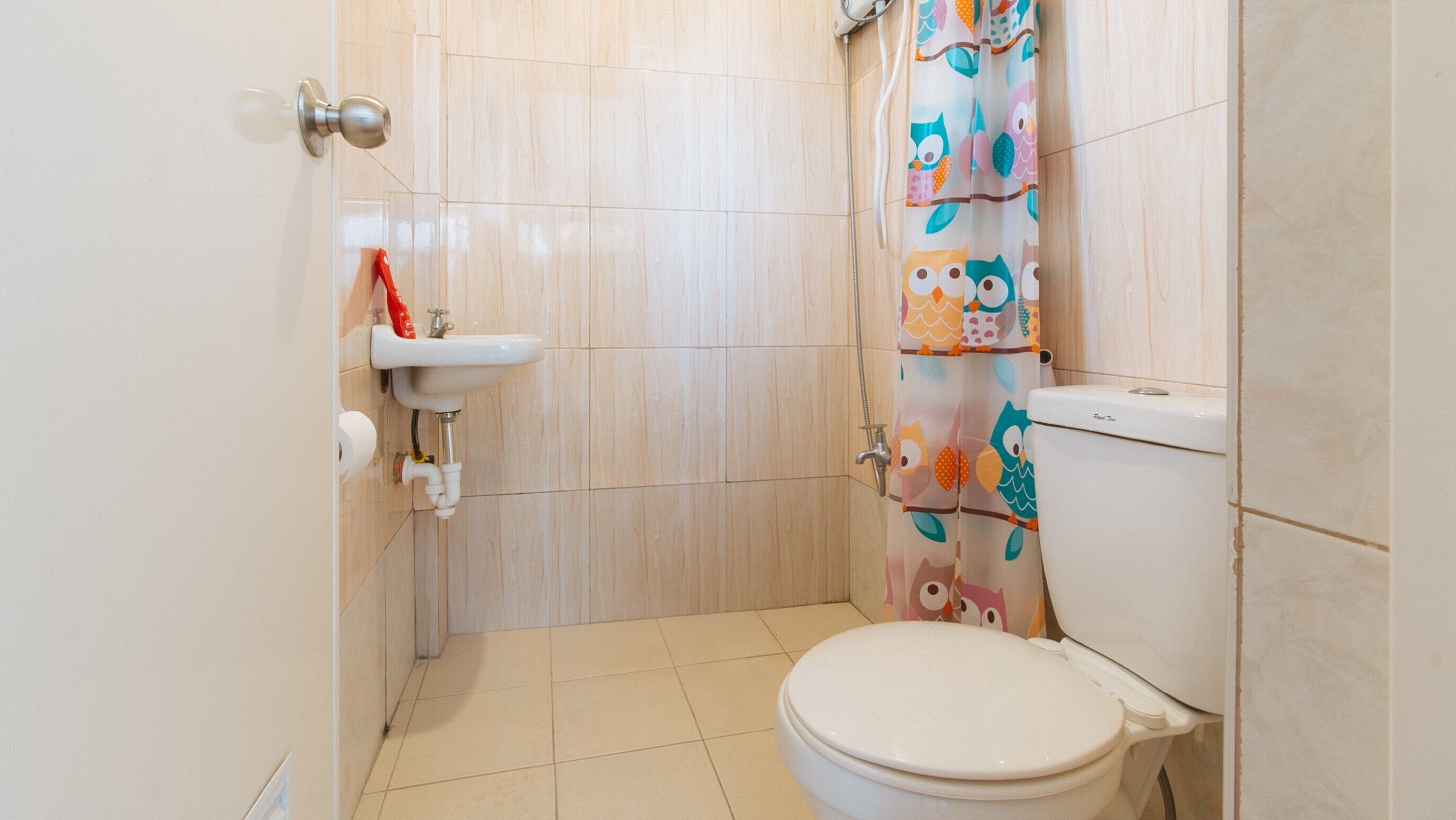 Een kleine badkamer met toilet, wastafel en douchegordijn met uilen.