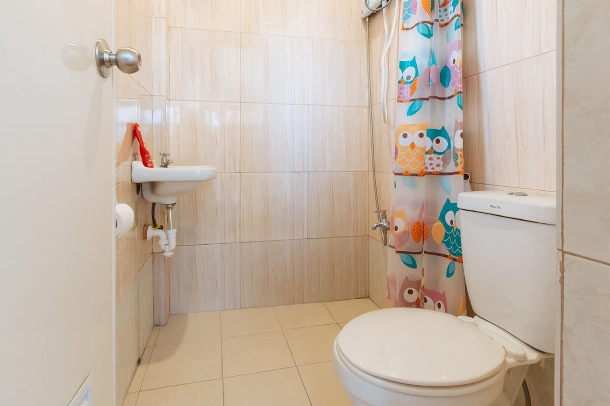 Een kleine badkamer met toilet, wastafel en douchegordijn met uilen.