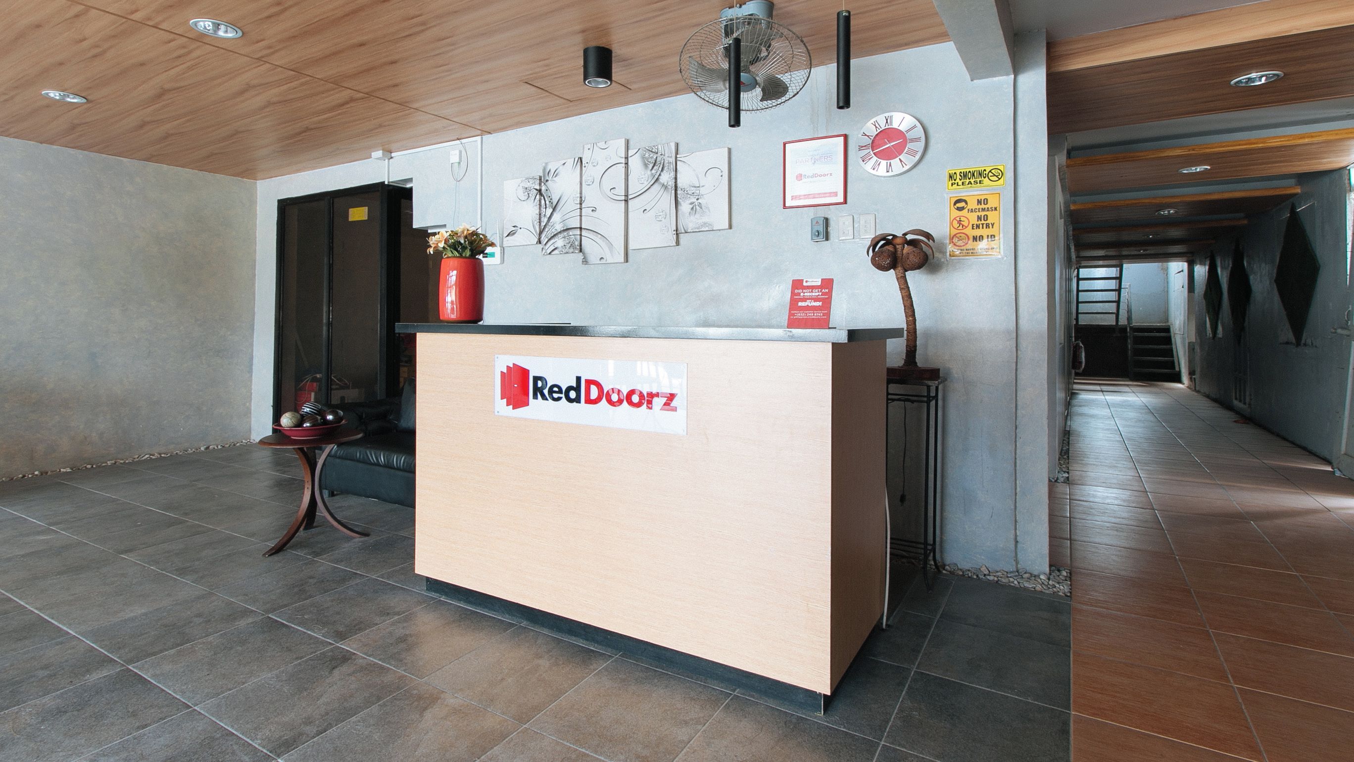 A reception desk with a RedDoorz sign, a clock, and various wall decorations.