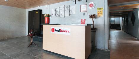 A reception desk with a RedDoorz sign, a clock, and various wall decorations.