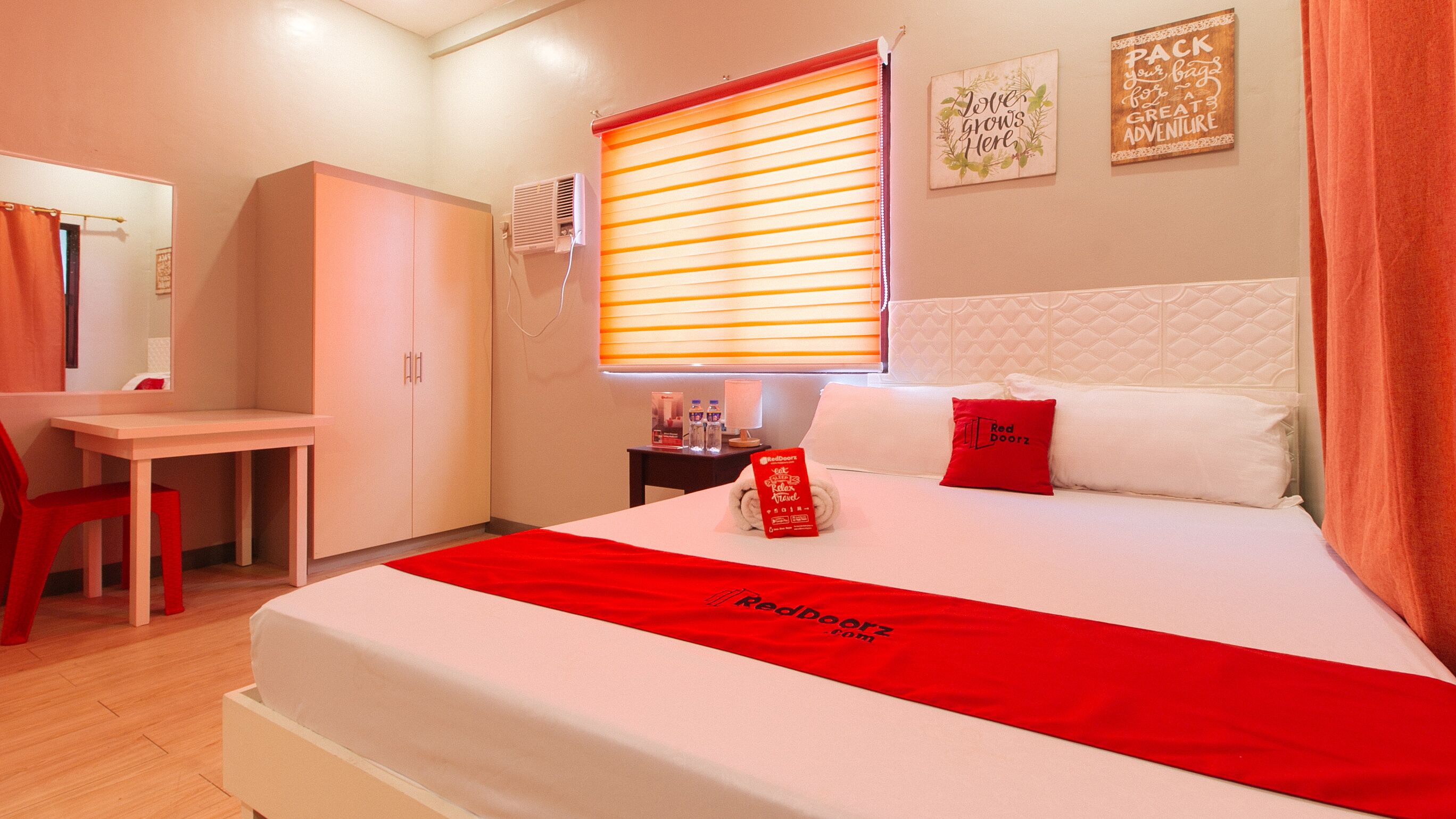 Een hotelkamer met een bed, een bureau en een kledingkast.