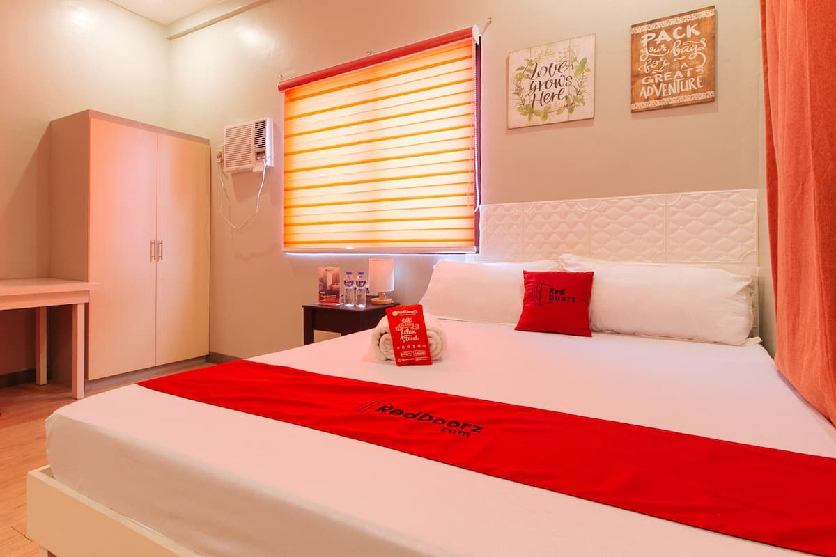 Een hotelkamer met een bed, een bureau en een kledingkast.