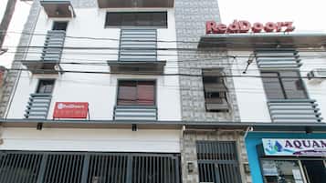 A building with a RedDoorz sign, a water feature, and a security gate.